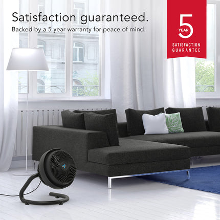 Modern living room with a black fan and a 5-year satisfaction guarantee badge.