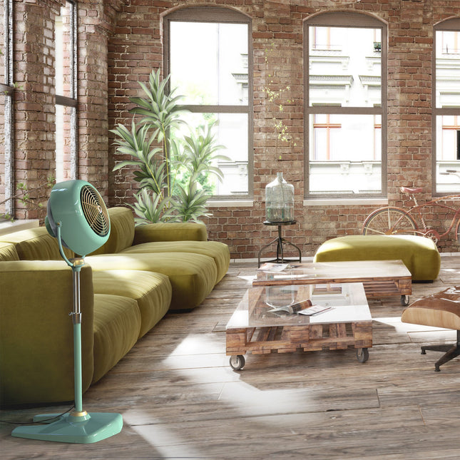 Modern living room with green floor fan, green sofa, wooden coffee table, and brick wall.