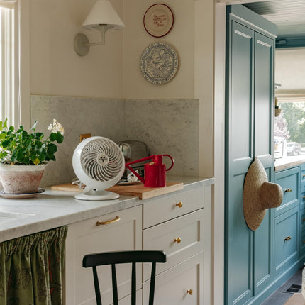 Kitchen interior with white cabinets, a black chair, and decorative elements including a white fan
