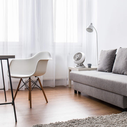 Modern living room with gray sofa, white fan, and small table.