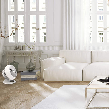 Modern living room with a white sofa, coffee table, and white floor fan.