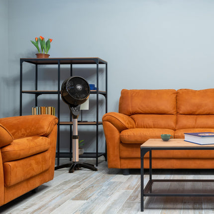 Living room with orange sofa, coffee table, and decorative items against a gray wall.