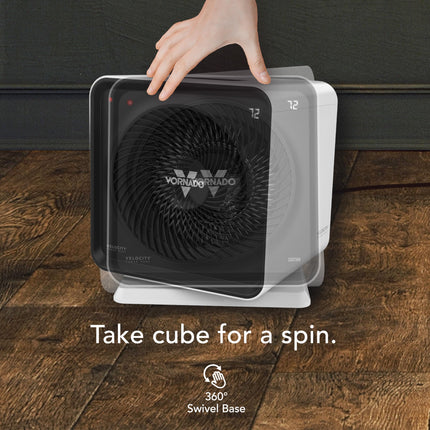 Vornado cube heater on a wooden floor with a hand lifting it, featuring the Vornado logo.