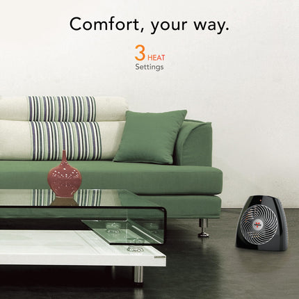 Modern living room with a green sofa, glass coffee table, and a small black heater.