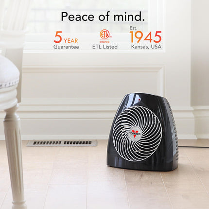Black space heater on a tiled floor with certification logos and text in the background.