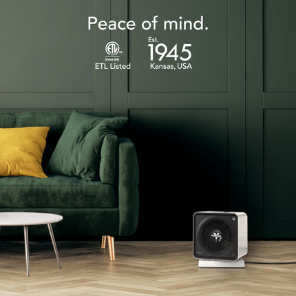 Small space heater on a wooden floor with a green couch and wall in the background, featuring ETL Listed and Interlock branding.