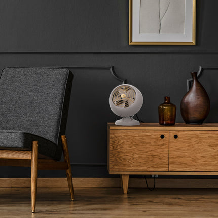 Modern living room with wooden cabinet, gray chair, and decorative items against a dark wall.