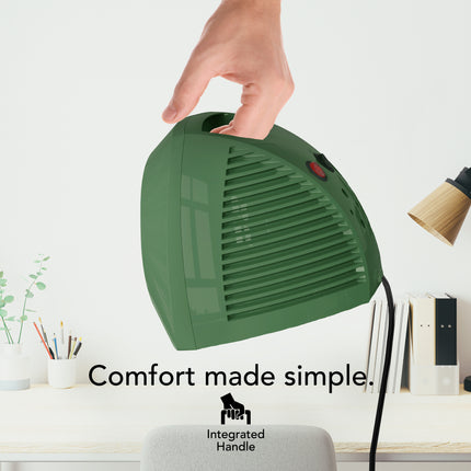 Green handheld space heater with a hand holding it, placed on a desk with office items.