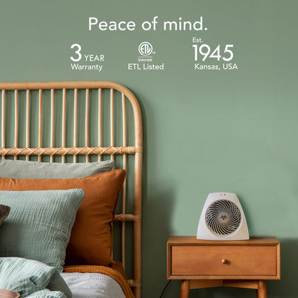 Bedroom with wooden headboard, pillows, and small nightstand with heater against a green wall.