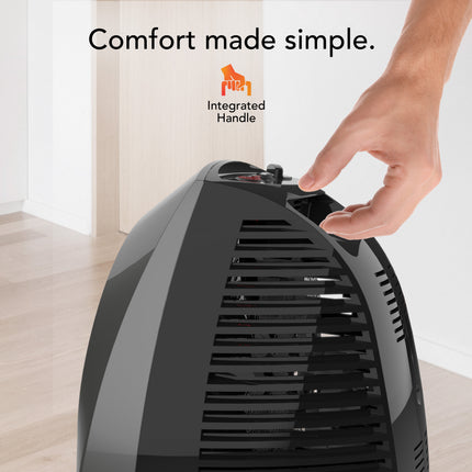 Black space heater with a hand reaching to press a button, set against a neutral background.