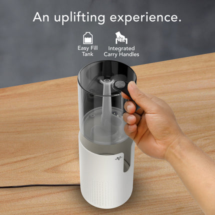 Hand holding a white and black humidifier tank with text 'An uplifting experience' and features listed.