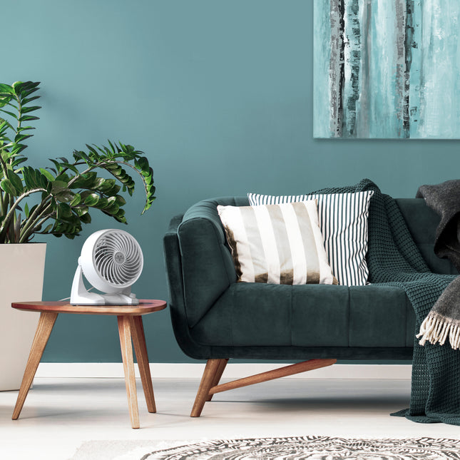 Modern living room with a green sofa, wooden side table, and plant.