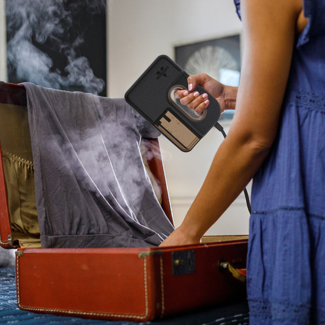 Person using a garment steamer on packed away shirt.