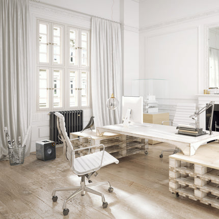 Modern office space with a desk, heater, chair, and large windows.