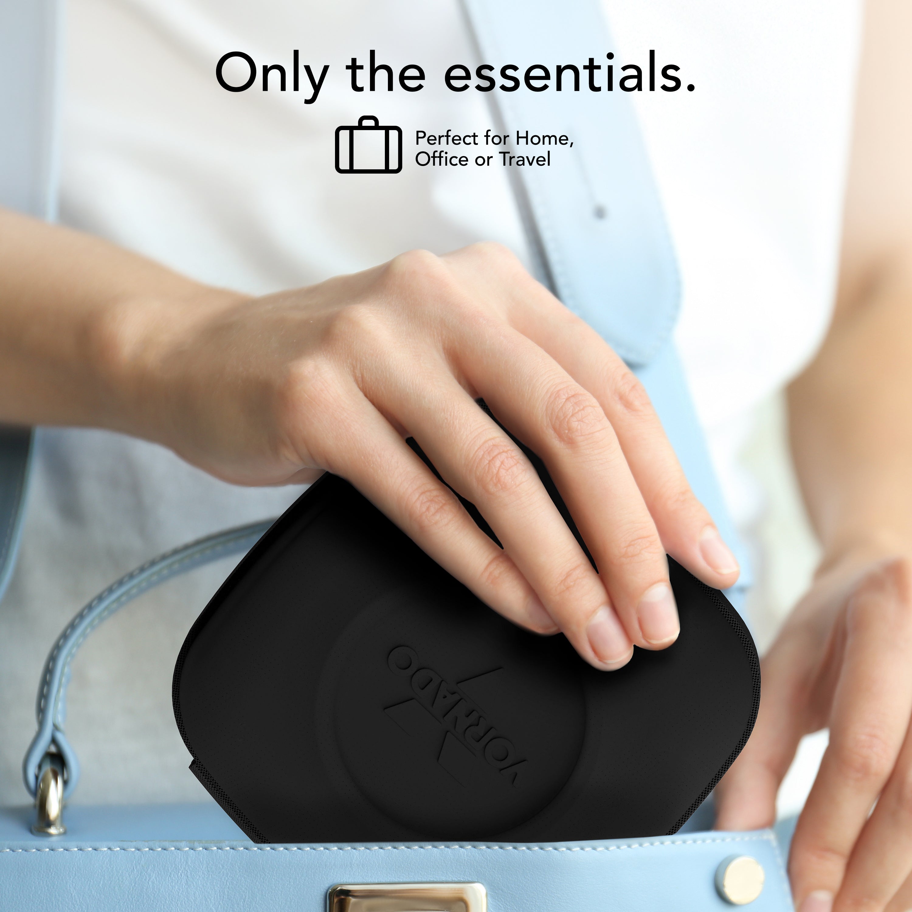 Person holding a black fan case with 'Vornado' branding, placed inside a blue handbag.