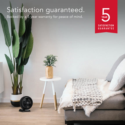 Living room with a bed, plants, and a small table, featuring a 5-year satisfaction guarantee.