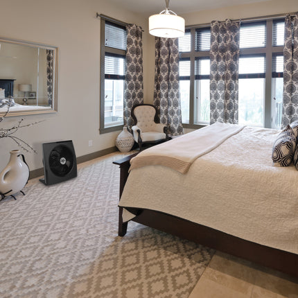 Modern bedroom with a bed, chair, and large windows.