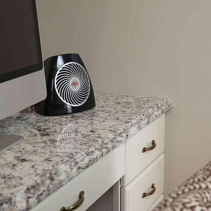 Black and white heater on a granite countertop next to a computer monitor.