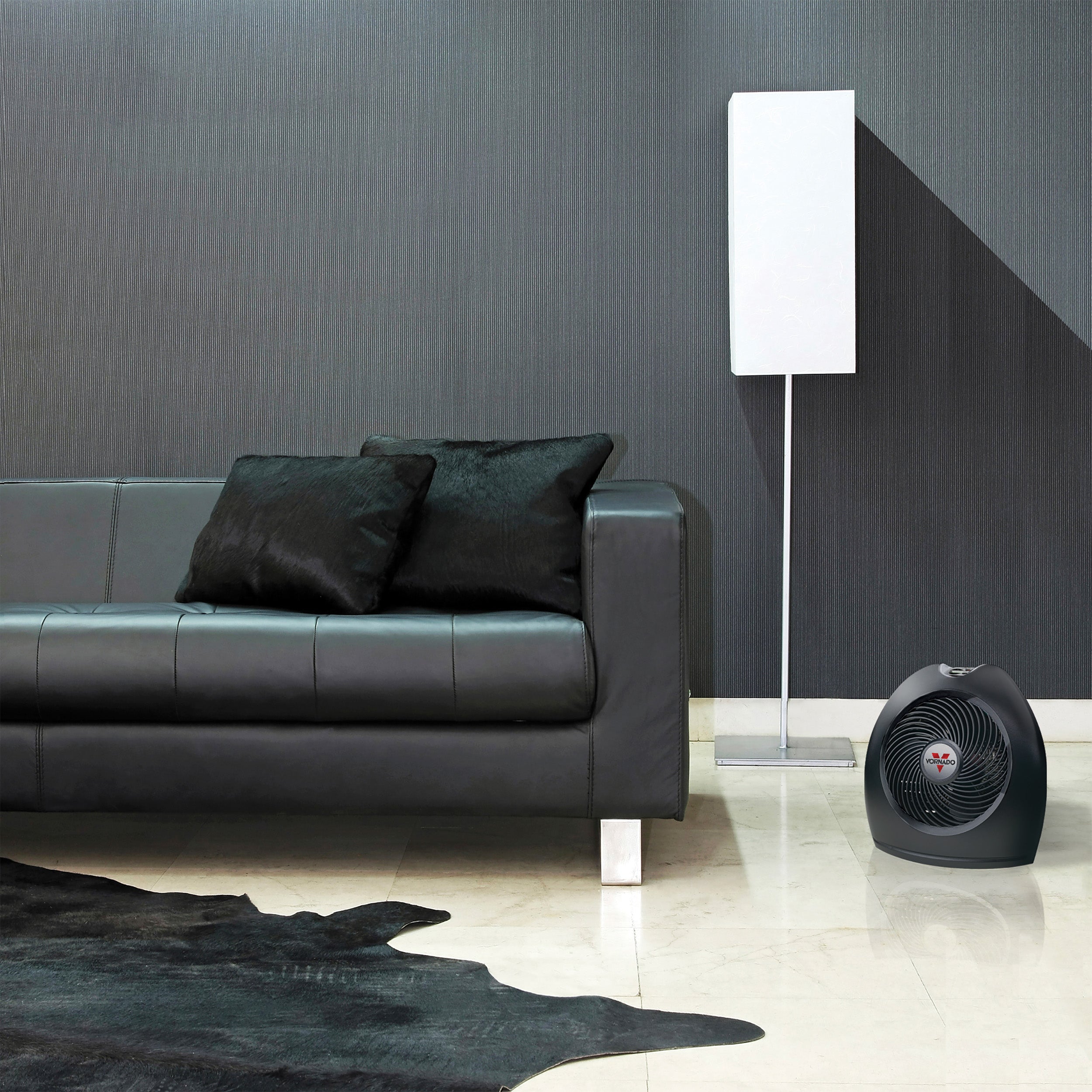 Modern living room with a black leather sofa, floor lamp, and portable heater