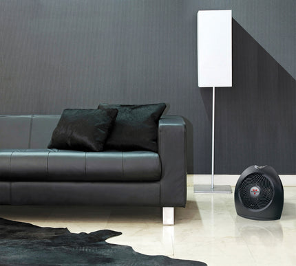 Modern living room with a black leather sofa, floor lamp, and portable heater