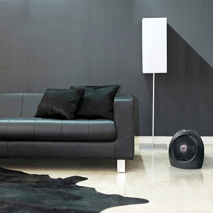 Modern living room with a black leather sofa, floor lamp, and portable heater