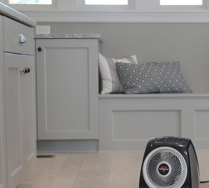 Black space heater on a tiled floor with a gray wall and window in the background