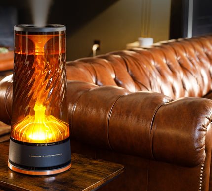 Decorative humidifier with flame-like design on a wooden table in front of a brown leather sofa.