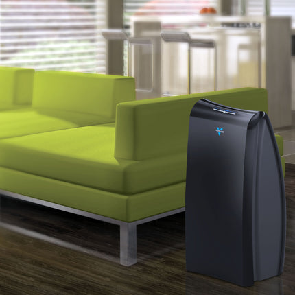 Air purifier next to a green sofa in a living room setting
