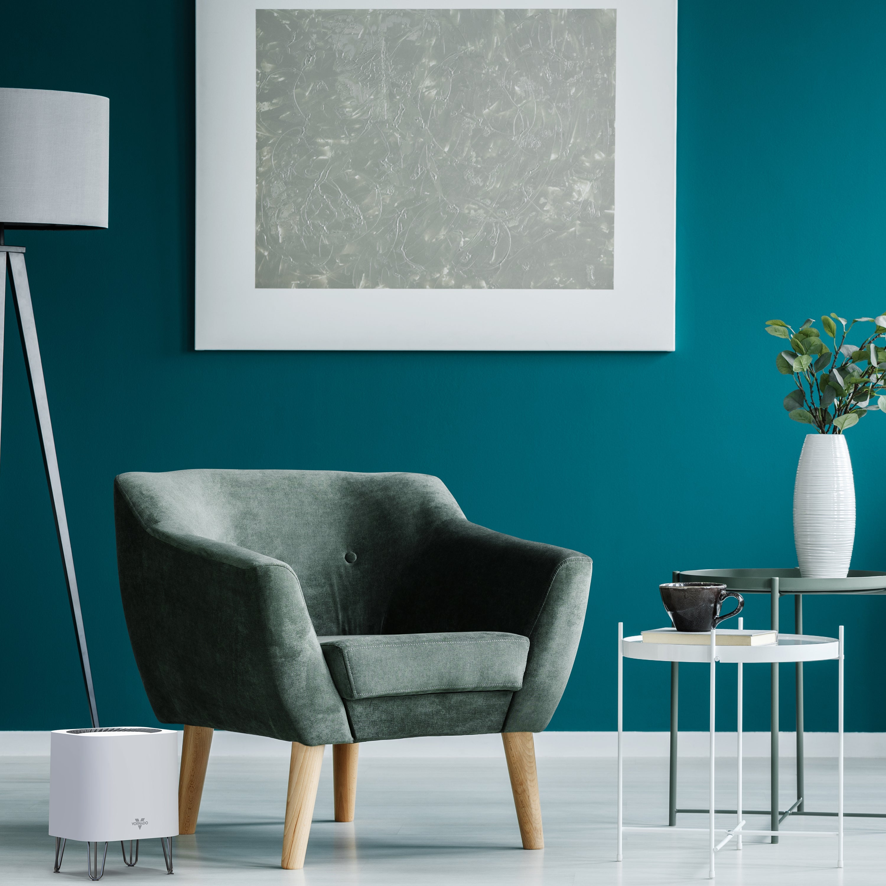 Modern living room with a gray armchair, teal wall, and air purifier.