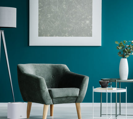 Modern living room with a gray armchair, teal wall, and air purifier.