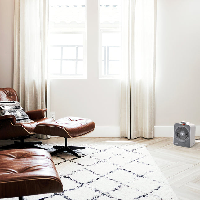 Modern living room with brown leather chair and ottoman on a white and black patterned rug.
