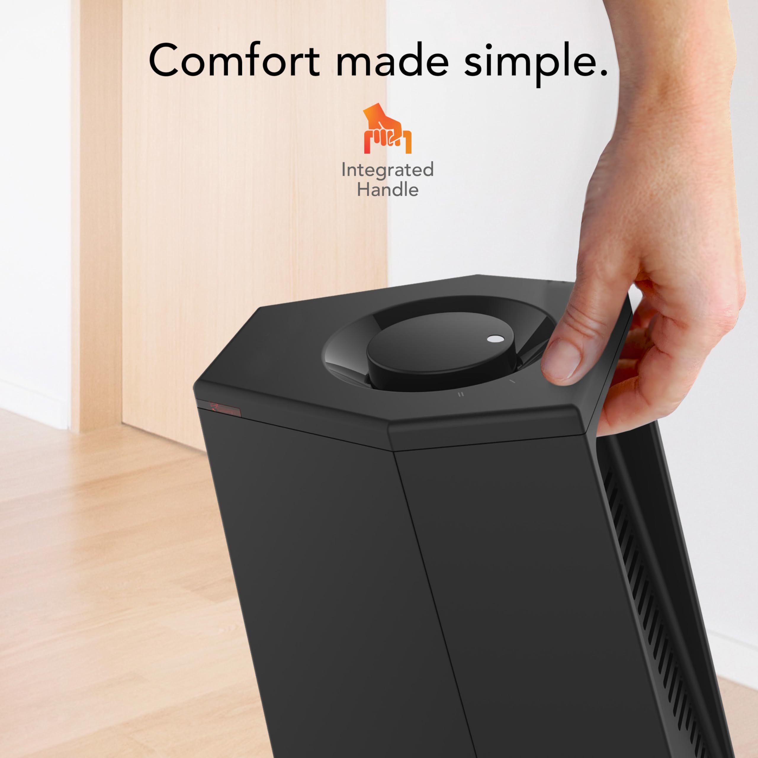Black heater with integrated handle being held by a hand, against a light background.