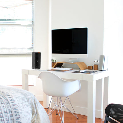 Modern bedroom with a white desk, desk heater, and computer setup.