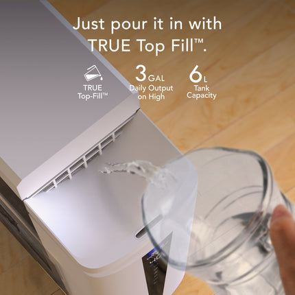 Person pouring water into a appliance labeled 'TRUE Top Fill' with text about capacity and output.