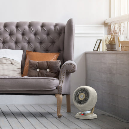 Vintage heater on a wooden floor next to a gray tufted sofa with cushions.
