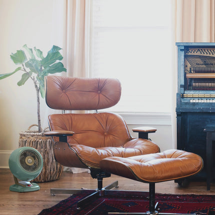 Brown leather lounge chair with ottoman in a room with a plant and vintage-style heater.