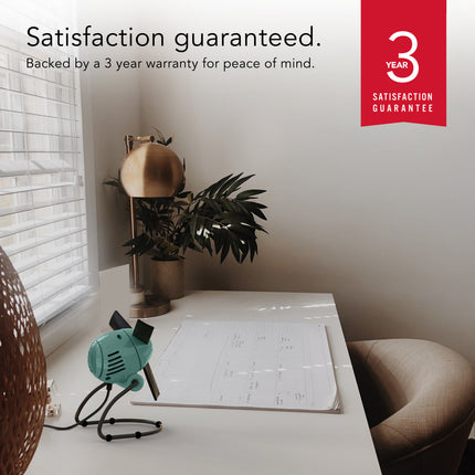 Desk setup with a plant, Zippi fan, and calendar, featuring a 3-year satisfaction guarantee.