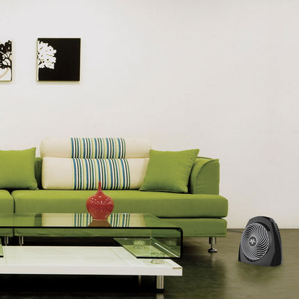 Modern living room with a green sofa, glass coffee table, and a small black fan.
