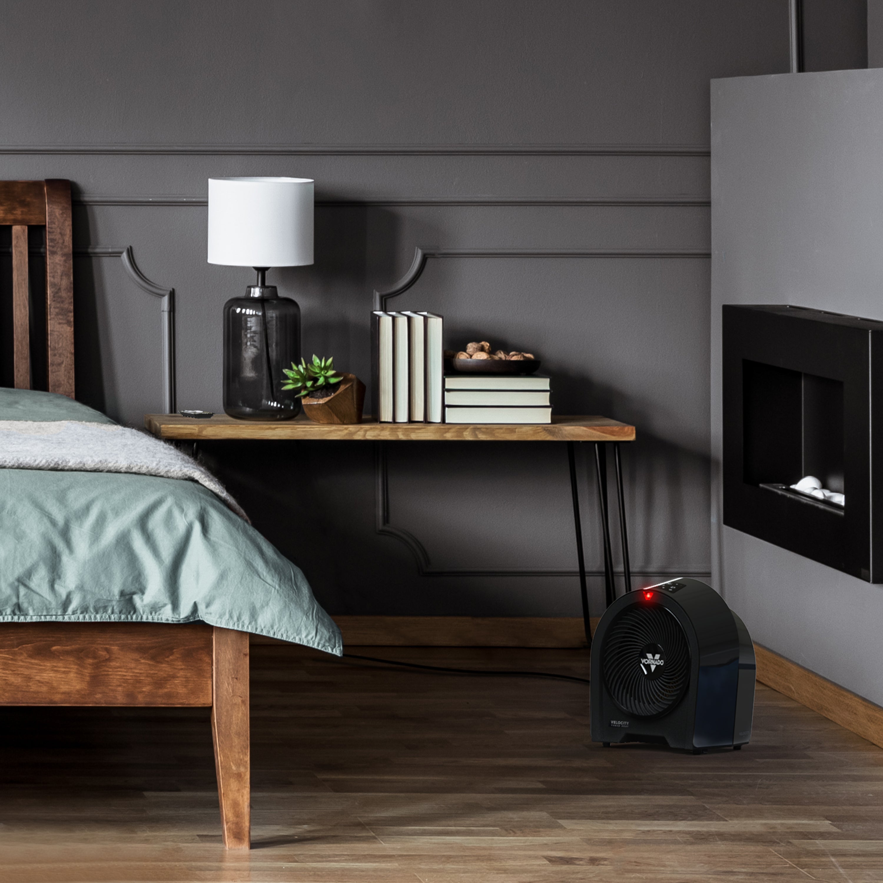 Modern bedroom with wooden bed, nightstand, and wall-mounted fireplace behind a black heater