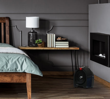 Modern bedroom with wooden bed, nightstand, and wall-mounted fireplace behind a black heater