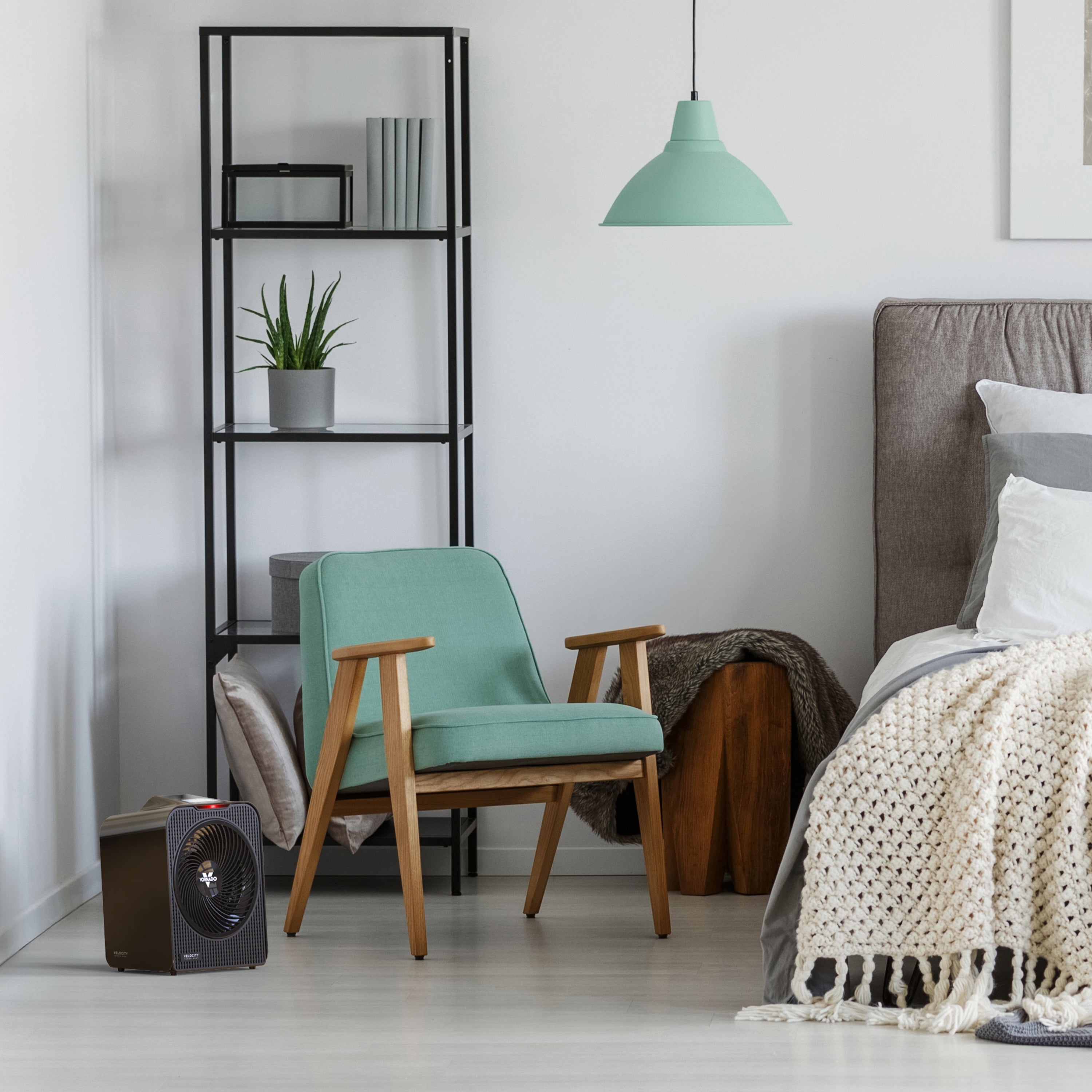 Modern bedroom with heater, teal armchair, bookshelf, and bed.