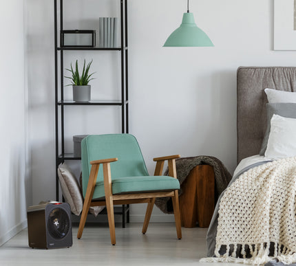 Modern bedroom with heater, teal armchair, bookshelf, and bed.
