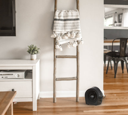 Decorative ladder with a striped towel in a living room setting next to a black heater