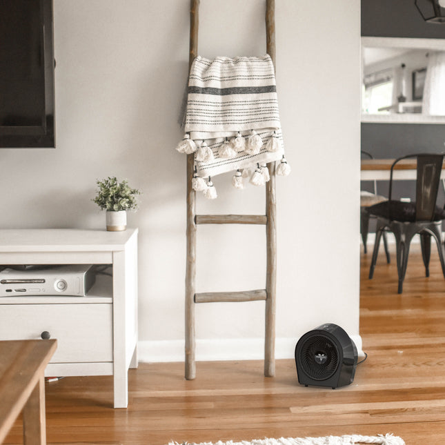 Decorative ladder with a striped towel in a living room setting next to a black heater