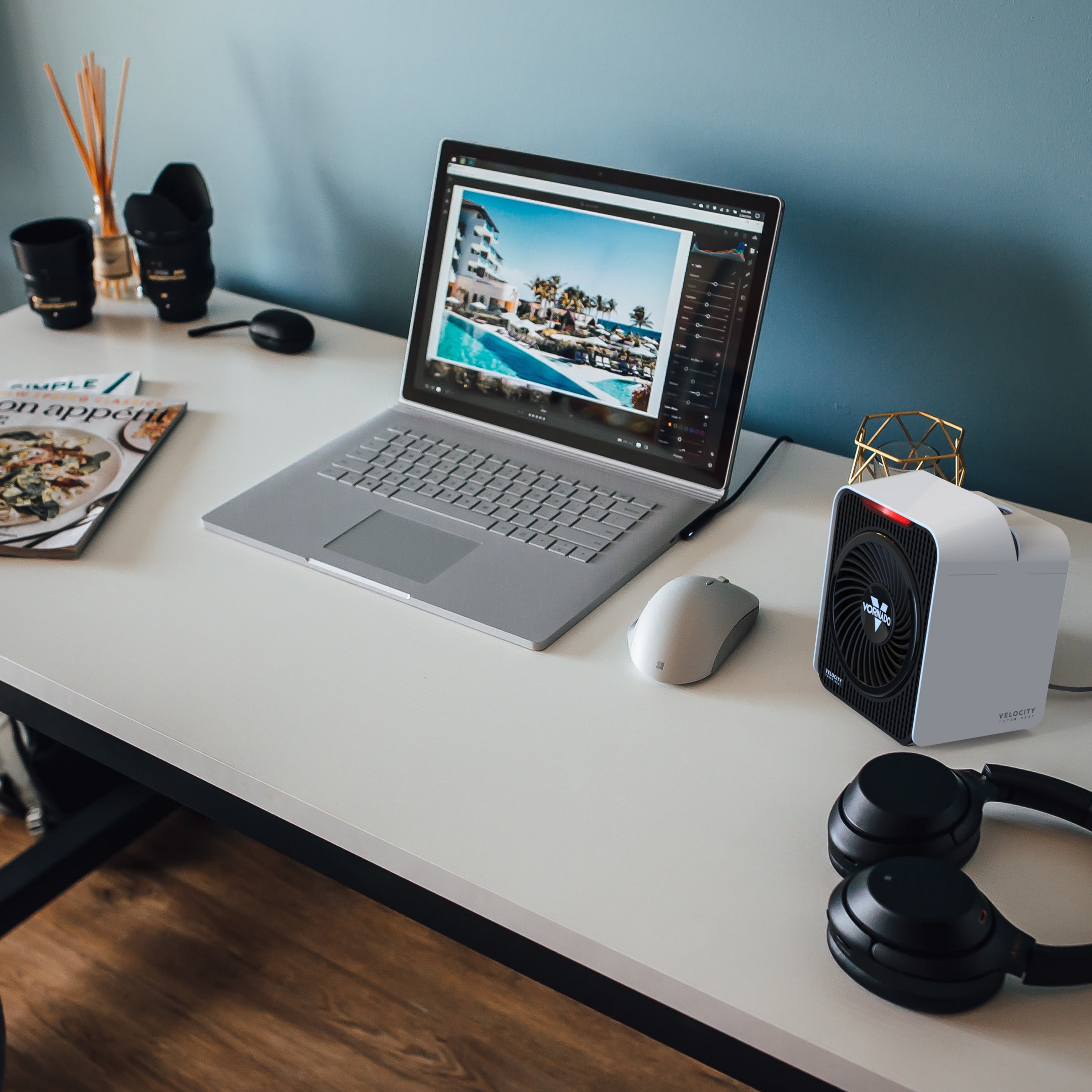 Laptop on a desk with a mouse, headphones, and a small heater.