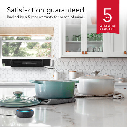 Kitchen counter with cookware, a window fan in a window, and a 5-year satisfaction guarantee badge.