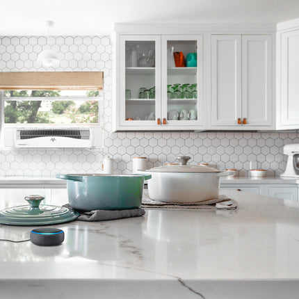 Modern kitchen with white cabinets, marble countertop, and hexagonal tile backsplash. A white vornado window fan is present in the kitchen window