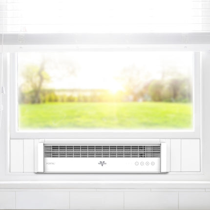 Window fan installed in a white window with a blurred outdoor view