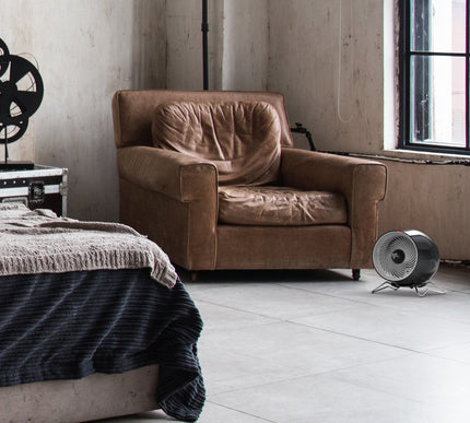 Brown armchair in a room with a window and a floor fan.