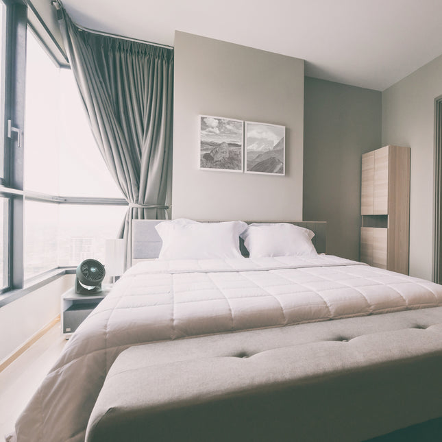 Modern fan in a bedroom with a bed, nightstands, and wall art.